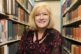 Photo of a smiling woman in a library. Link to Life Stage Gift Planner Ages 60-70 Situations.